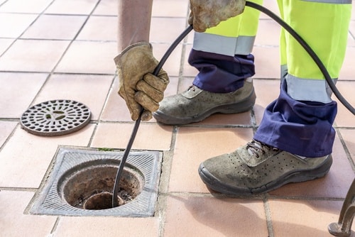 A plumber cleans a drain.