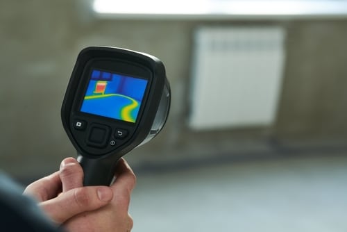 A plumber points a thermal imaging device to detect a slab leak