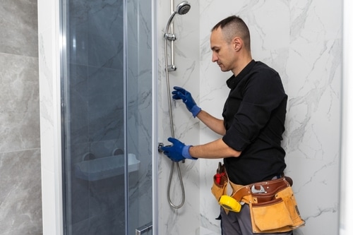 A plumber installs a showerhead.
